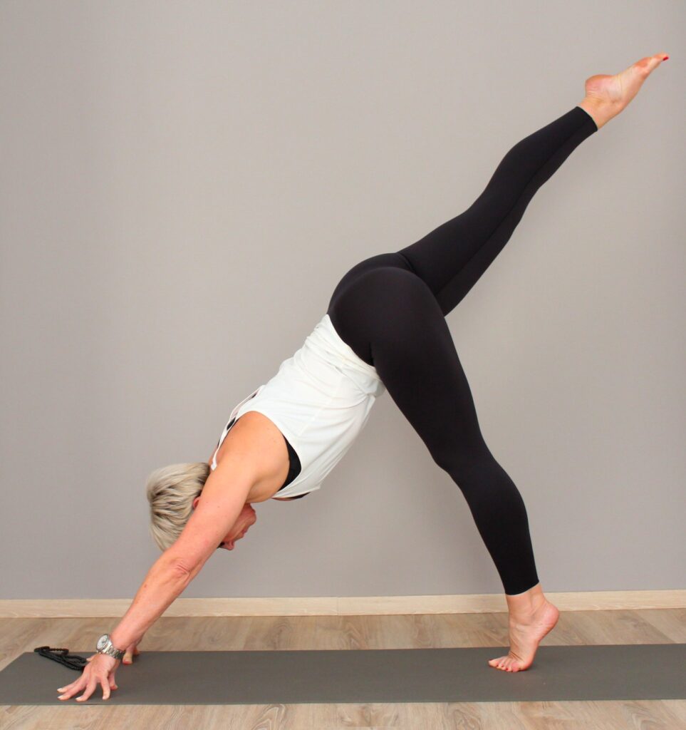 Karin Möller auf der Yogamatte, die Hände am Boden und ein Bein nach oben gestreckt